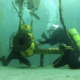 Two commercial divers in a training pool working on fixing a pipe.