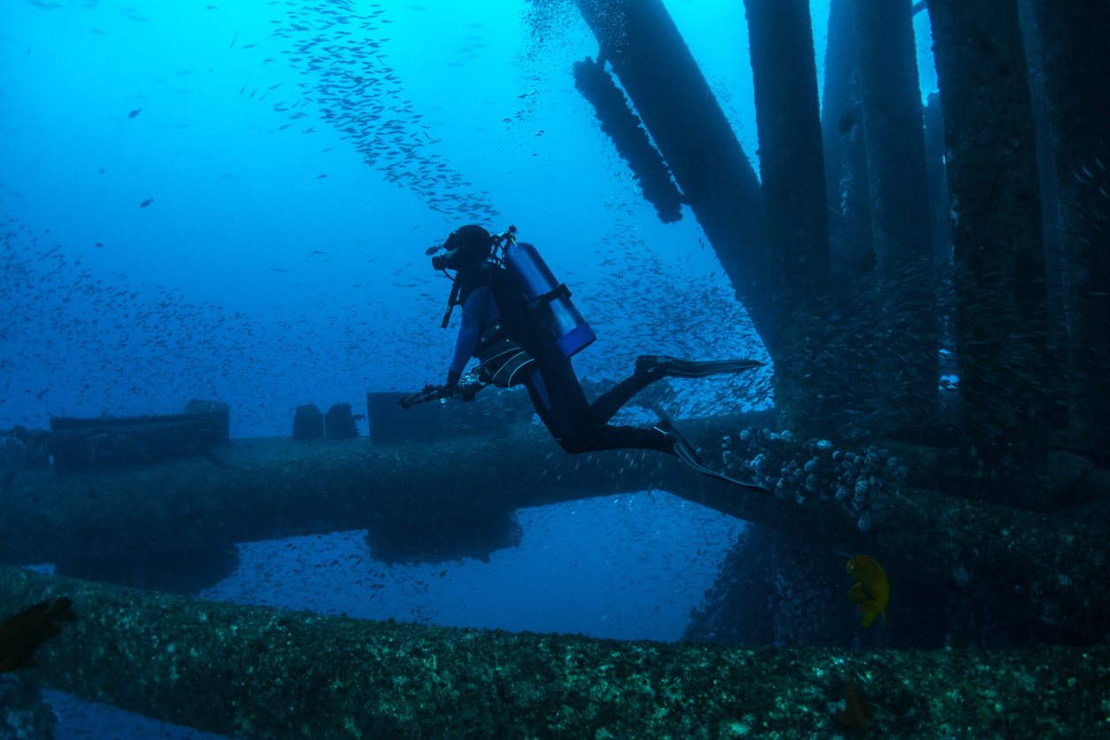 An underwater NDT specialist swims by a bridge he's inspecting.