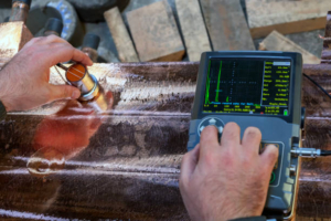 Operator performs ultrasonic inspection on copper casting. Ultrasonic testing (UT) is a family of non-destructive testing techniques based on the propagation of ultrasonic waves in the object