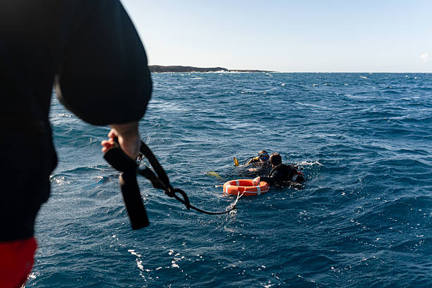 someone holding rope to rescue tube while diver is in the water rescuing someone